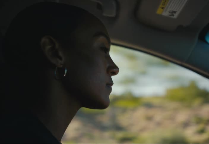 A woman is driving a car on a road
