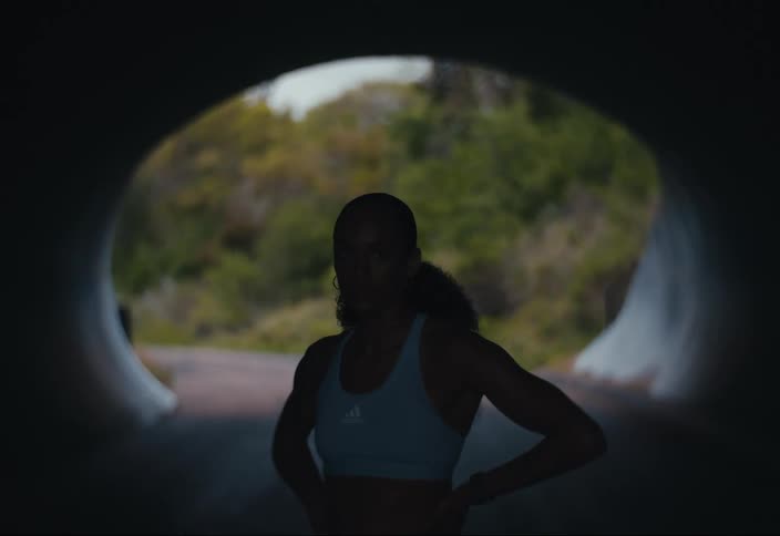A young woman is standing in a dark tunnel