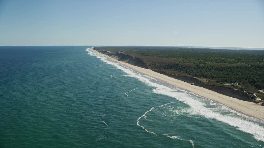 Aerial view of ocean waves breaking against long beach