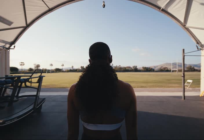 A woman walks out to a field from a gym