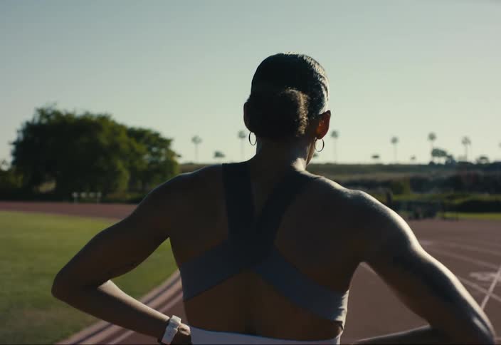 A athlete walking on a track field with her hands on her waist