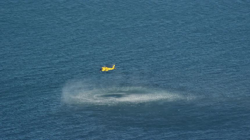 From an aerial perspective a rescue helicopter hovers above the shimmering sea