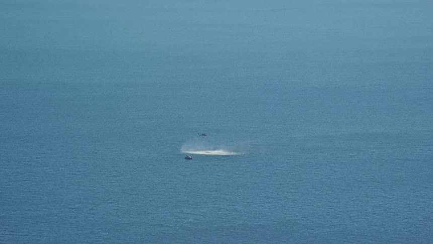 A helicopter is flying over the ocean