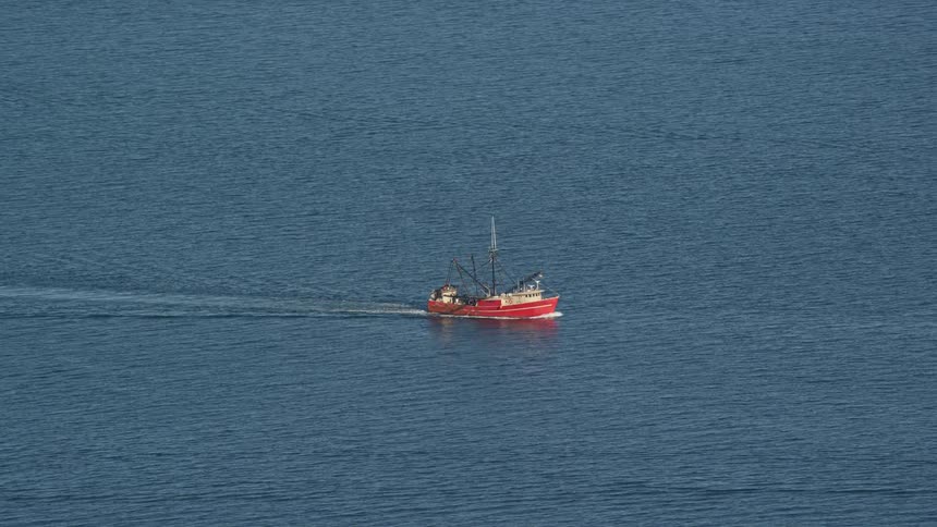 A small fishing boat sailing in a blue sea