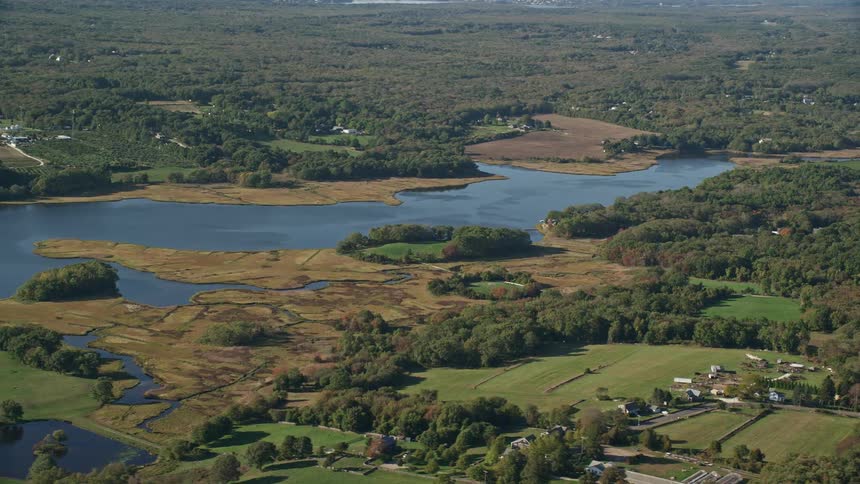 A rural region with few human buildings and many trees has a river crossing the pieces of land