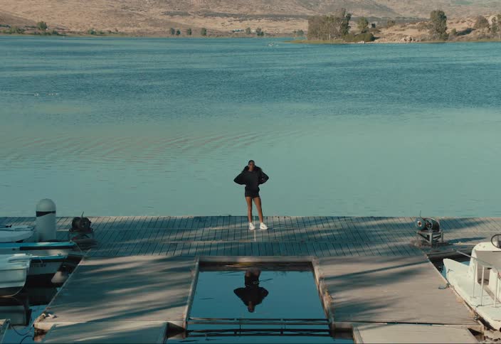 Woman stands on a dock overlooking a lake