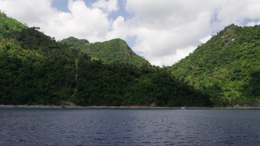 Flowing water beside tree covered hills