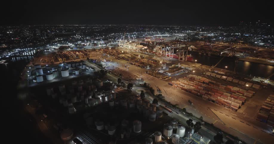 Aerial panorama of a port with containers and the city on the horizon at night