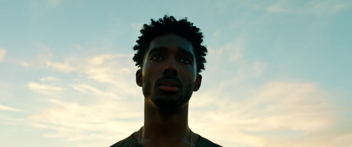 A black man in deep thought while standing at sunset