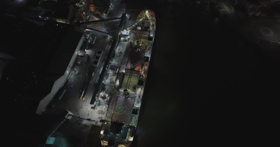 A cargo ship on a pier with crane in a night