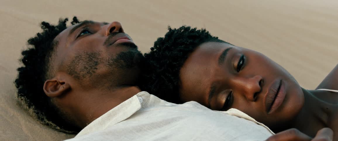 Tearyeyed woman cuddles against man as they lie on sand