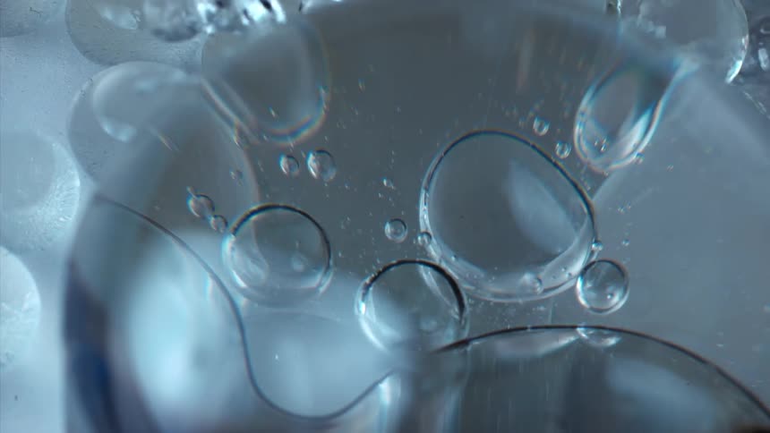 Bubbles float and stretch as they move in a clear liquid