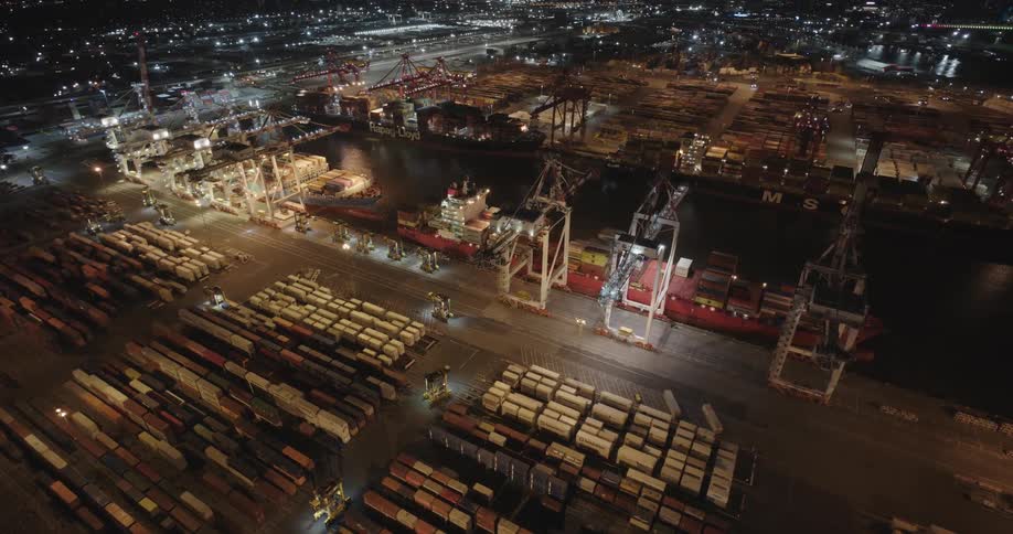 Aerial view of shipping containers and cranes on a port at night