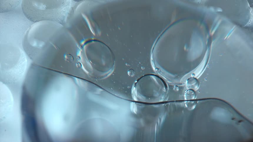 Bubbles float and stretch as they move in a clear liquid