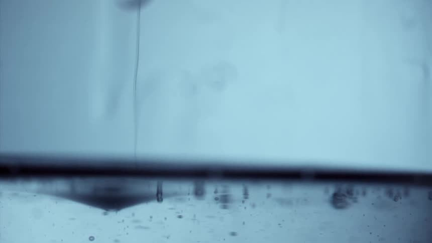 Droplet falling into moving water in slow motion