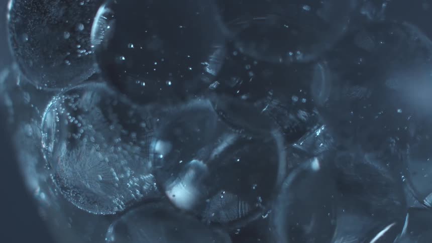 Clear spheres rotate through colorless liquid