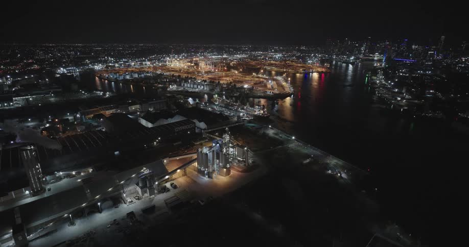 Water bordering city skyline at night reflects nearby lights