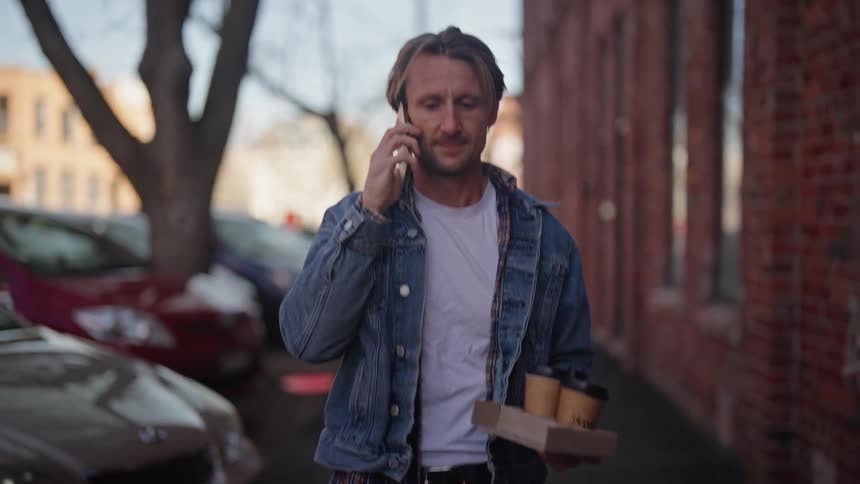 A man walking on the sidewalk while talking on phone