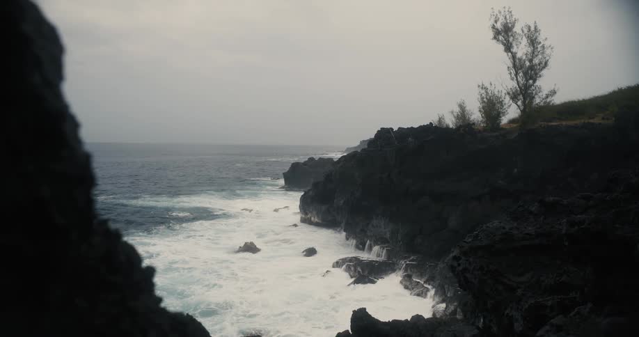 A dark cliff with waves crashing against it