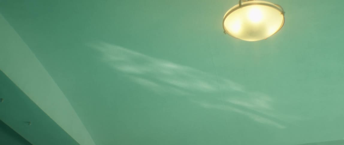 Light bouncing on the water surface on a pool reflecting on the ceiling
