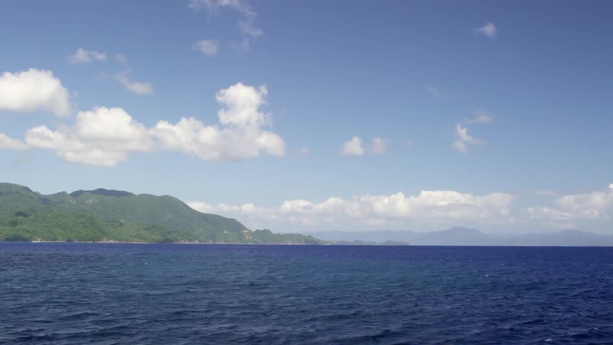 A blue sky with some white clouds over choppy waves