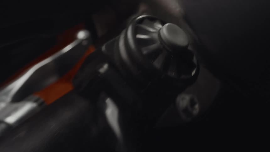 A person wearing a black glove presses a button on a vehicle engine