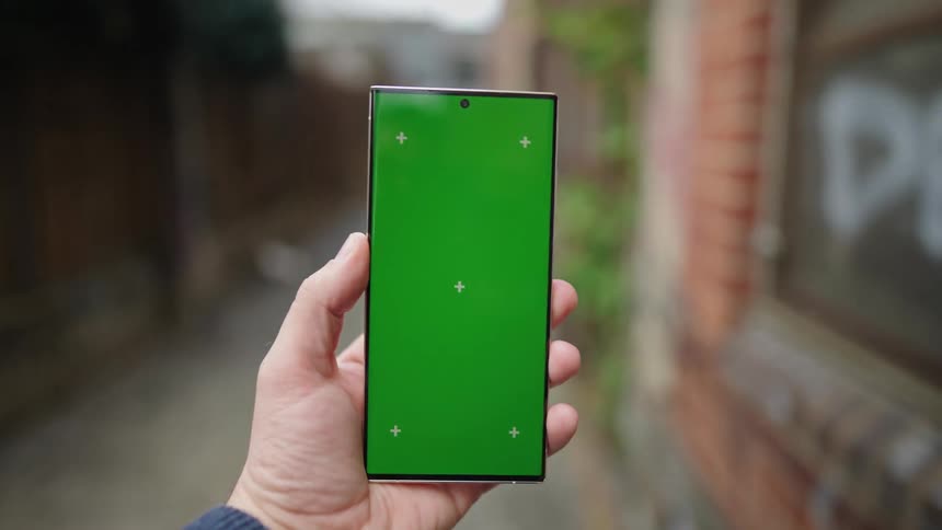 Person holding a smartphone with the screen on while walking down an alley