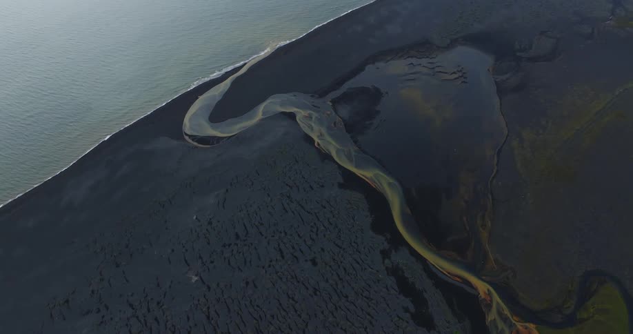 A colorful river on the black sand beach