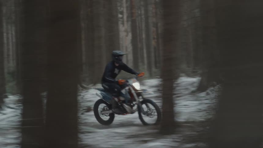 A man is racing his dirt bike through the forest