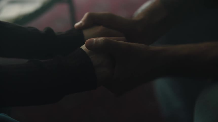 Two people hold hands and one of them makes a face on the others hand using their fingers