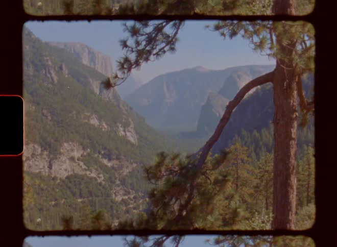A valley surrounded by forest and rocky mountains