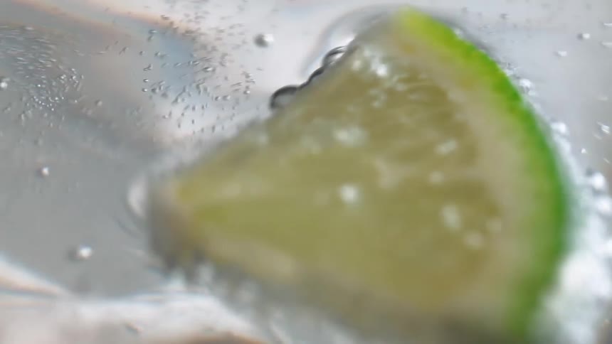 A piece of lime is floating in the carbonated water