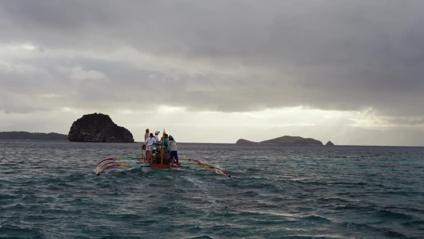 People ride a pontoon in the ocean at sunset