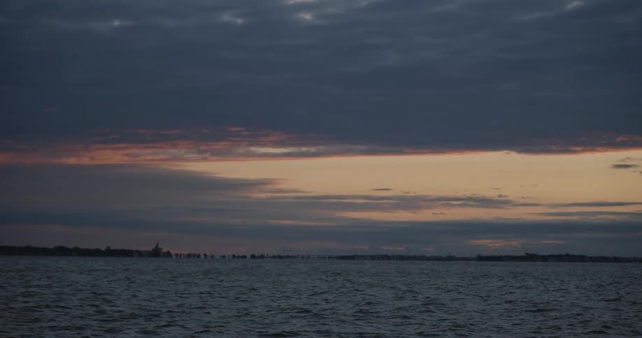 A calm sea with cloudy sky at sunset