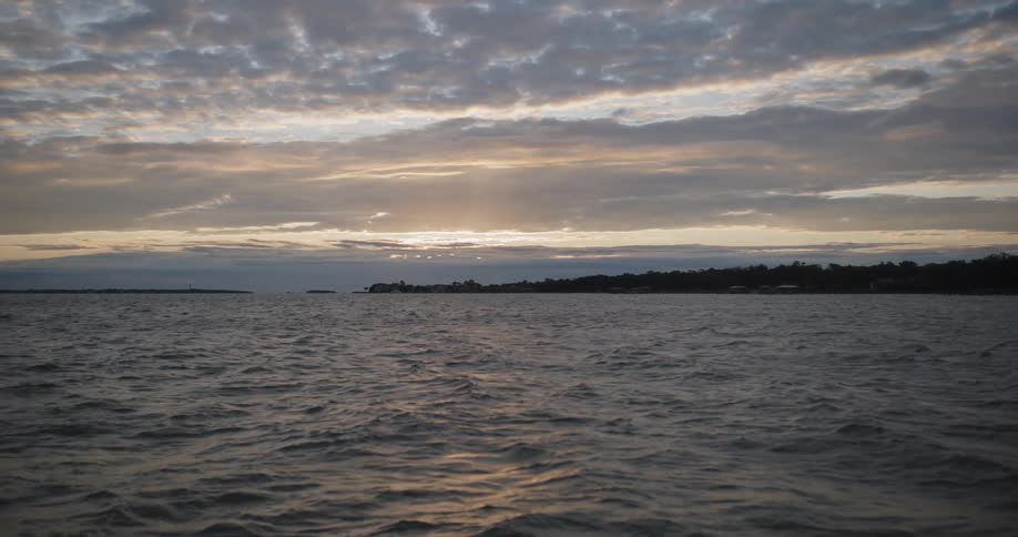 The sun is rising on the rough waters