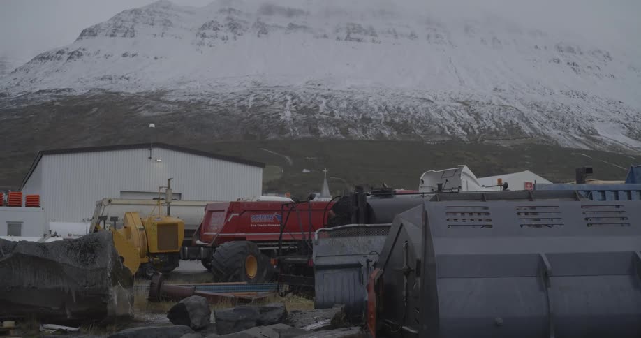 Panorama of parked heavy vehicles with a massive snowcovered mountain right behind