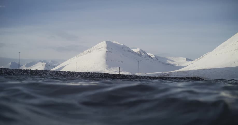 Ocean waves next to the snow covered mountains