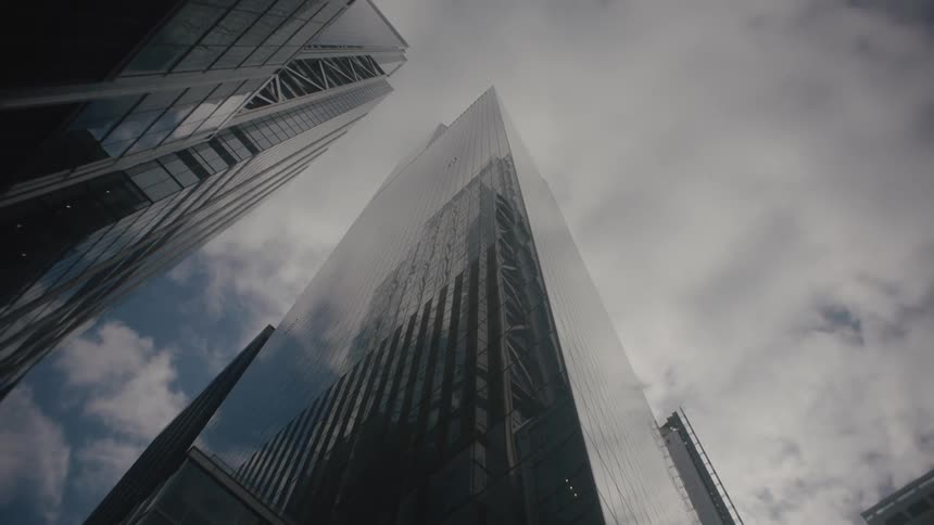 Downtown skyscrapers reflect each other and the overhead clouds