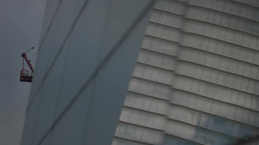 View of a massive mirrored building with a crane in the background