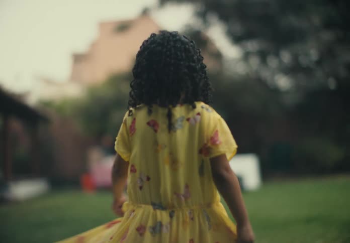 Girl holds dress skirt up while spinning in place in yard