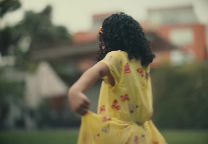 Girl walking in a backyard on the grass with her yellow dress