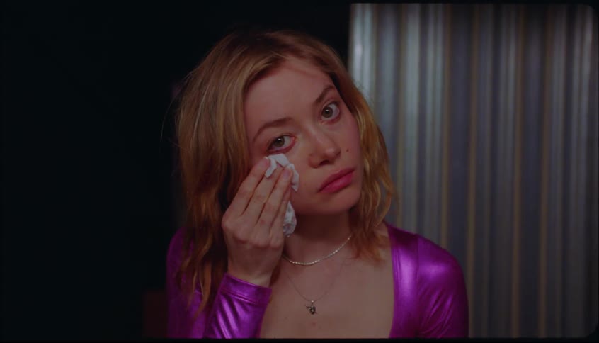 Young lady removing makeup on her face while seated in a room