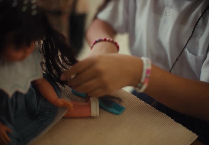 Closeup of a childs hands combing a dolls hair