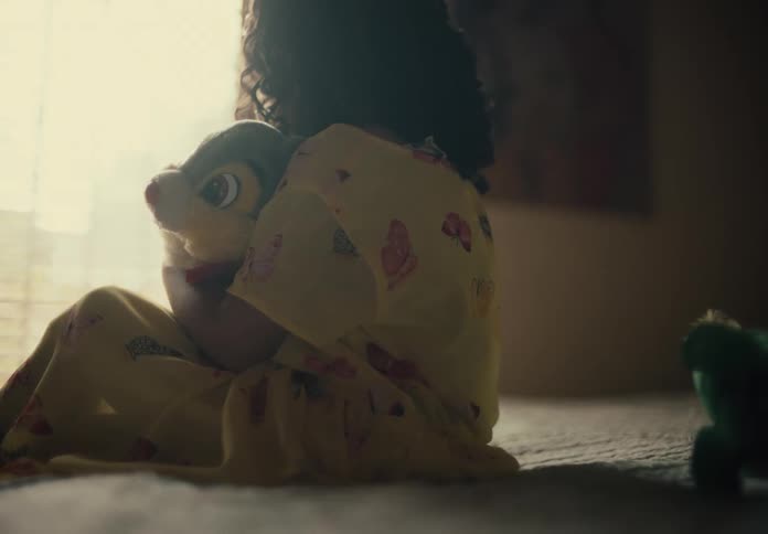 Little girl sitting on the bed hugging her plush toy