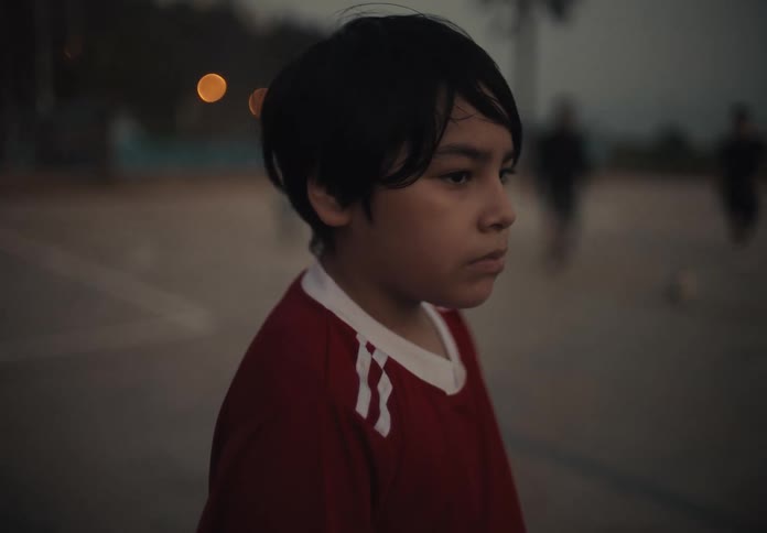 A young boy naturally looking in front of and behind people playing soccer