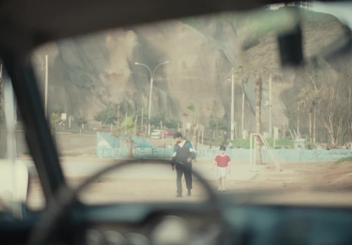 View from inside the car of two people an adult and a child approaching