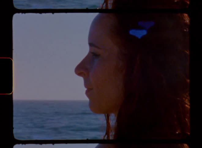 Profile of a redheaded woman standing in the sun next to water during day time