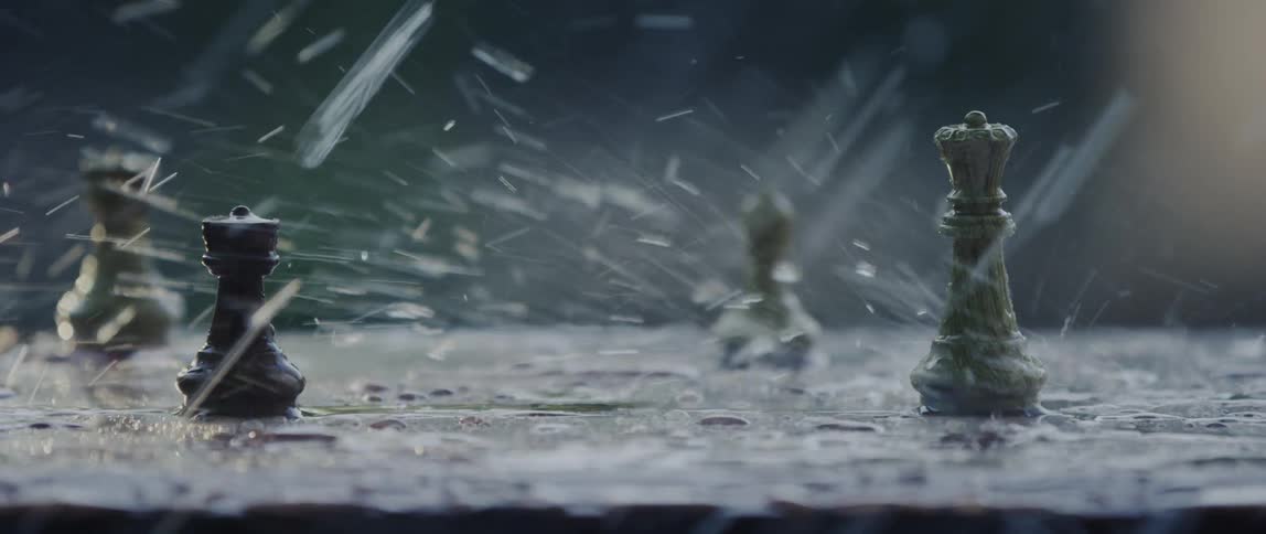 Rain falls onto chess pieces on wet surface