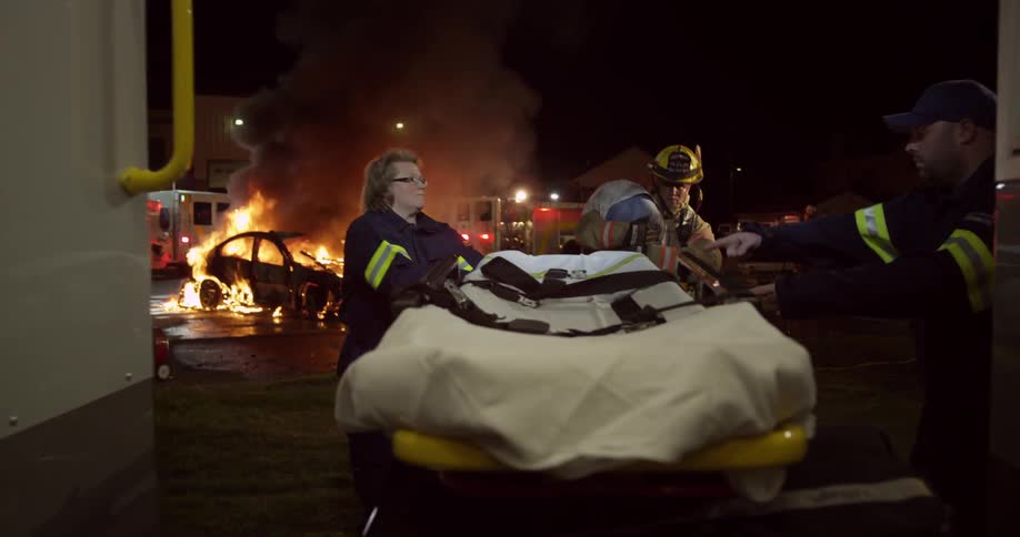 A stretcher is removed from an ambulance and a person is carried over to it