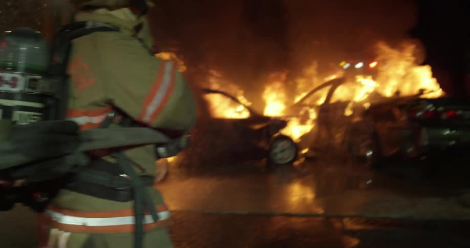 Firemen line up to hose cars on fire